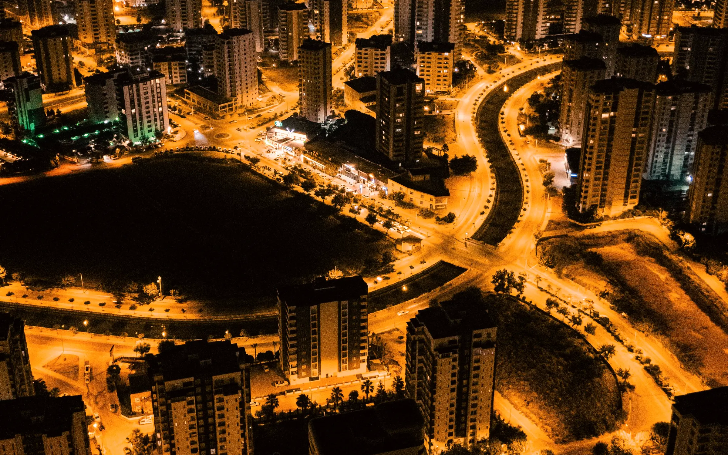 Vista aérea de uma cidade à noite, com ruas e prédios iluminados em tons de âmbar